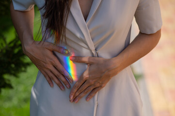 Faceless woman catching rainbow ray with her hands outdoors. 
