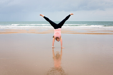 athletic woman in fitness clothes, cartwheel on beach, fun healthy lifestyle, busy mum mom mother,...