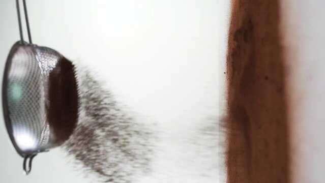 Sieving brown powder on the table against white background
