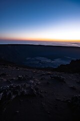An otherworldly vista of an empty crater, its jagged rim silhouetted against the glow of a distant horizon, Generative AI