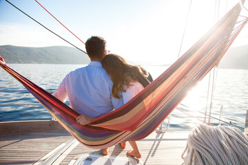 Couple in love relaxing in beach hammock on yacht at sea. Man and woman traveling, enjoying summer...