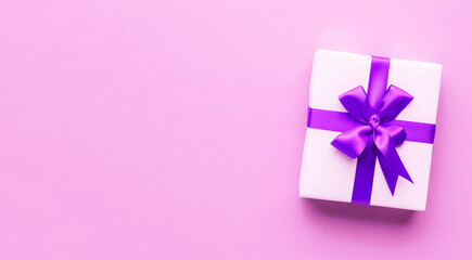 Obraz premium Decorative gift box with purple bow and long ribbon on a light pink background. Greeting card design for Christmas, New Year, Wedding, Mother's day, Easter, Valentine day.