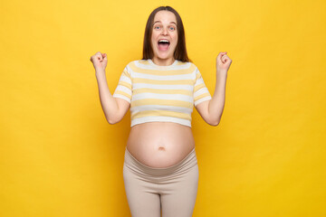 Extremely happy cheerful excited Caucasian pregnant woman in casual clothing posing isolated over...