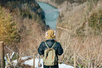 Woman tourist sightseeing View of Japan local train with Tadami river and bridge. Traveler travel...