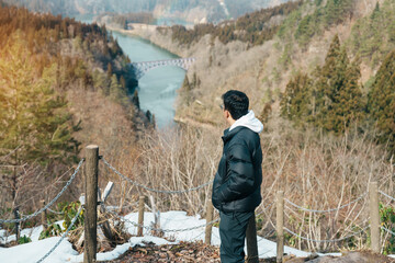 man tourist sightseeing View of Japan local train with Tadami river and bridge. Traveler travel at...