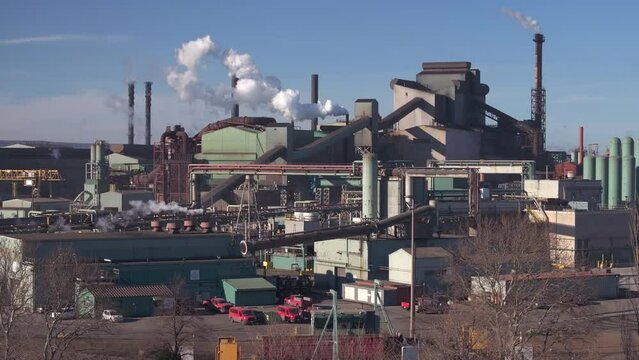 Industrial complex in Hamilton, Ontario with smokestacks against blue sky, wide shot