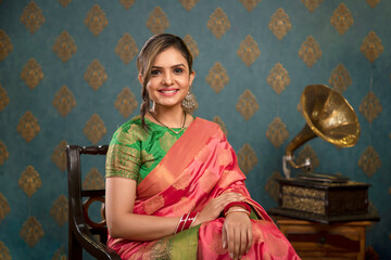 A Young Female Model Sitting On Chair In Saree For Diwali Festival
