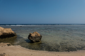 single coral rock in the water at the beach with deep blue sky