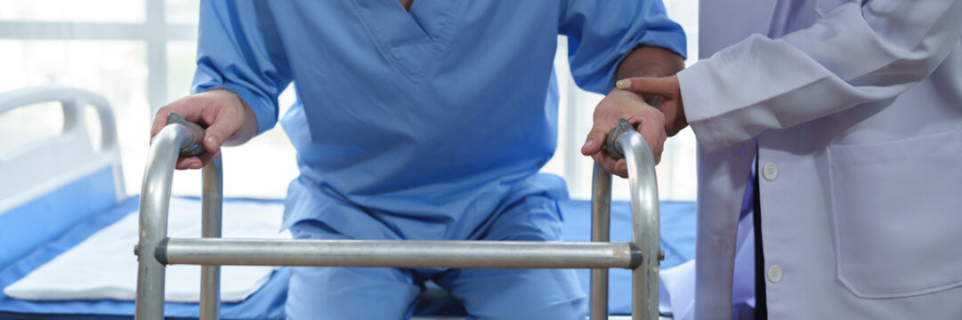 Physical therapist helps a male patient use a walker to practice walking. Support yourself from recovery from sore legs and ankles. Physical therapy service concept.