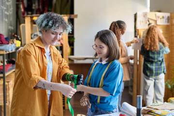 Waist up portrait of two teenage girls decorating prosthetics in inclusive crafting class