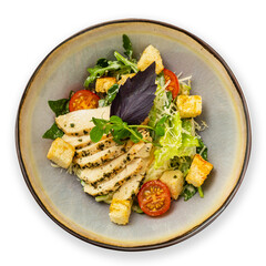 Caesar salad with chicken on a plate, top view, on a white background.