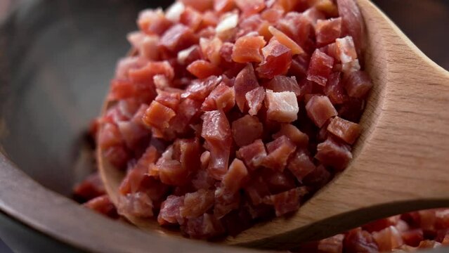 Diced Spanish jamon meat in kitchen wooden spoon. Cured serrano ham close up. Typical mediterranean ingredient