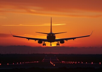 Commercial Airplane Landing on Runway at Sunset with Orange Sky
