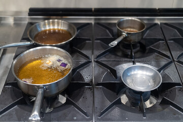 Kitchen stove top with boiling oil in a pot. Industrial kitchen equipment.