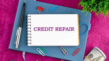 CREDIT REPAIR text written on a blank sheet of notepad in a composition with pens, paper clips,...
