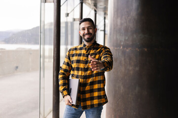 Engaging Hispanic Businessman Offering Handshake in Modern Urban Corridor