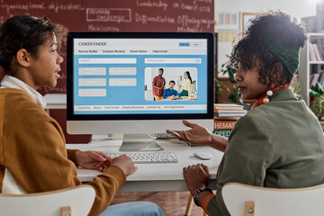 Side view of two Black students discussing career opportunities in college classroom