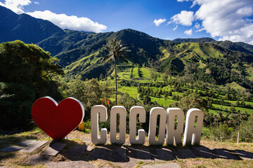 Sign Yo Love Cocora in famous entertainment center Valle del Cocora Valley with tall wax palm trees. Salento, Quindio department. Colombia travel destination.
