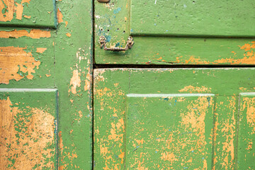 closed and locked wooden gate with green weathered paint.