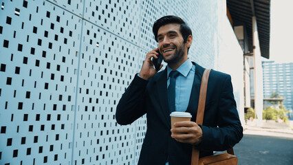 Smart business man using phone to talking about business investment. Happy manager walking at...
