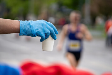 Runners of a marathon are provided with water at a hydration station. Running event, refreshment...