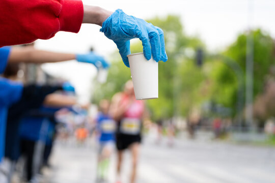Runners of a marathon are provided with water at a hydration station. Running event, refreshment point along the route of long-distance run.