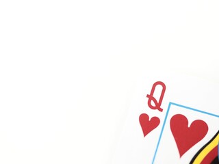 Close up of a Queen of hearts poker playing card in a corner on a white background with space for...
