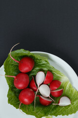 Radish sliced on a white plate with black background.