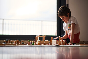 A young boy creating a magic world with his wood toys figures.