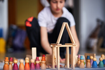 A young child behind his wood toys in the playroom