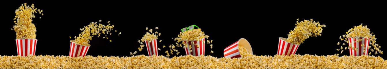 Scattered popcorn from paper striped bucket isolated on black background