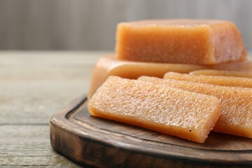 Tasty sweet quince paste on wooden table, closeup. Space for text