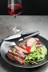 Delicious grilled beef meat served with greens and wine on grey table
