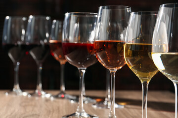 Different tasty wines in glasses on wooden table