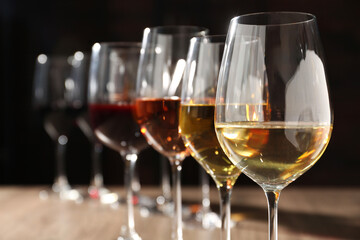 Different tasty wines in glasses against blurred background, closeup