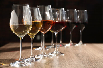 Different tasty wines in glasses on wooden table, space for text