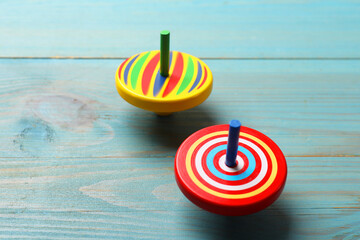 Bright spinning tops on light blue wooden table, closeup
