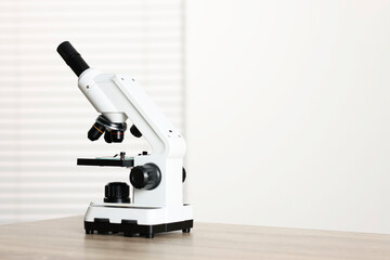 Modern microscope on wooden table. Space for text