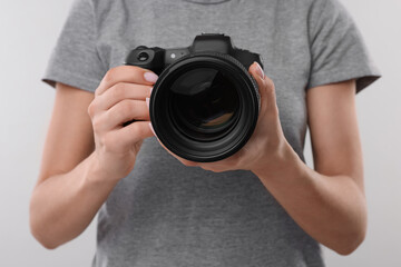 Photographer with camera on light grey background, closeup