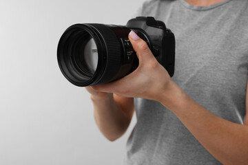 Photographer with camera on light grey background, closeup