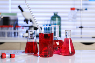 Laboratory analysis. Different glassware with red liquid on white table indoors
