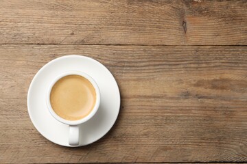Aromatic coffee in cup on wooden table, top view. Space for text