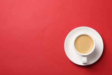 Aromatic coffee in cup on red background, top view. Space for text