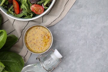 Tasty vinaigrette in bowl, vinegar and salad on grey table, flat lay. Space for text