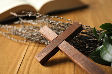 Cross and willow branches on wooden table, closeup