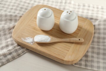 Spice shakers with salt on white wooden table