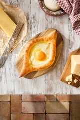 Traditional Georgian Adjarian Khachapuri with Egg and Cheese on a Wooden Table, Bright Morning Light