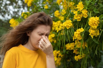 Portrait of beautiful young allergic woman is suffering from pollen allergy or cold on natural...