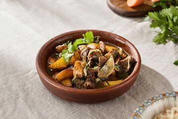 Traditional Georgian Ojakhuri with Potatoes and Meat Served in Rustic Clay Pot on Linen Tablecloth...