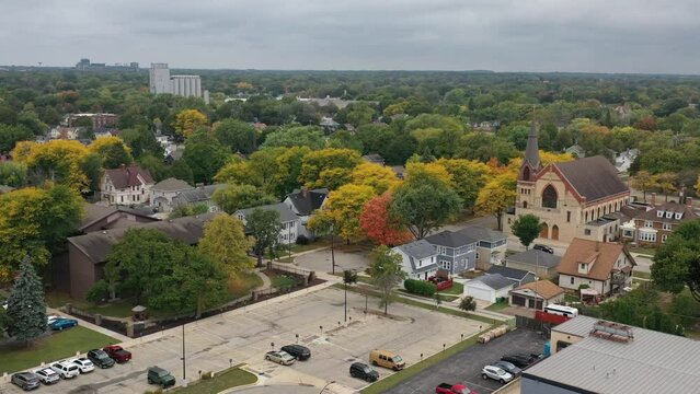 Aerial view of Green Bay Wisconsin autumn neighborhood with church in the foreground and Lambeau Field in the distance, drone push forward